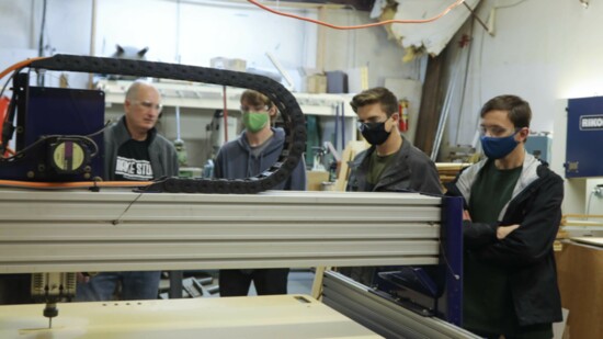 Gregg Lehman discusses a project with Peyton Gilbert, Micah Cramer and Max Mackiewicz at the CNC router. 