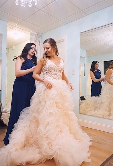 Abbie Paklos assists a bride-to-be try on a dress. 