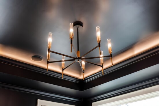 A darkly painted ceiling contrasts beautifully with a light chandelier.