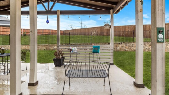A pergola provides a shady spot to grill while enjoying this large backyard. 