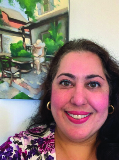 Local artist Mehrnaz Moussavi poses in front of her painting that features her mother. It's this month's cover art.