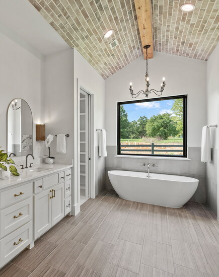 The owners bath pairs a serene soaking tub with layered natural materials, creating a private retreat within the award-winning suite.