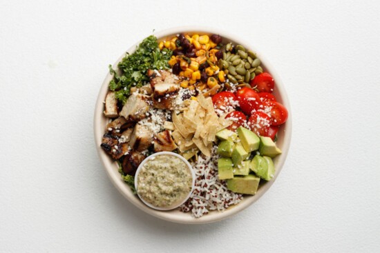 The popular Chicken Mamacita Bowl contains grilled chicken, corn & black bean salsa, tomatoes, toasted pumpkin seeds, tortilla strips, cojita, and a tomatillo 