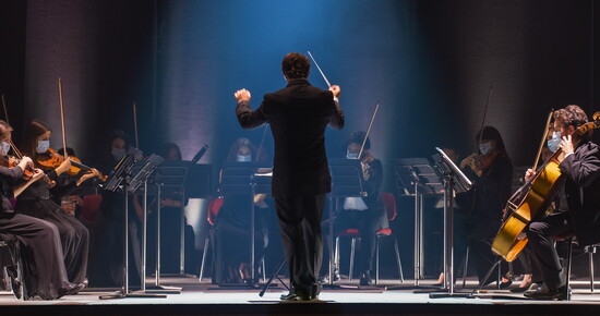 The conductor leads in full motion, each gesture guiding the music.