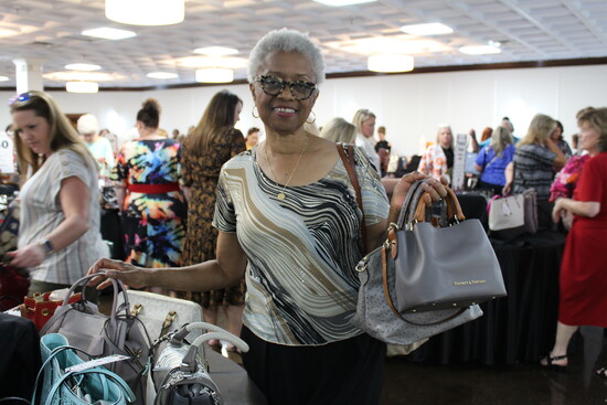 A delighted guest enjoys her purchase at the 2025 Power of the Purse event