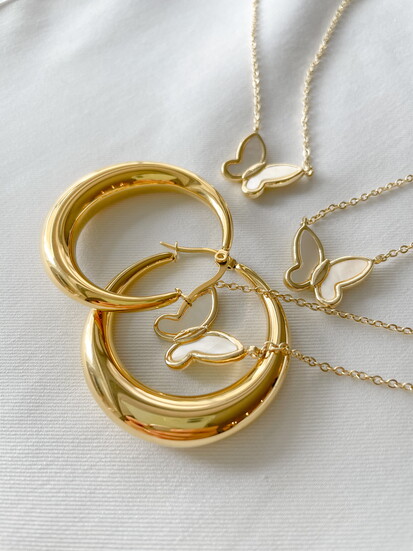Chunky gold hoop earrings with delicate necklaces.