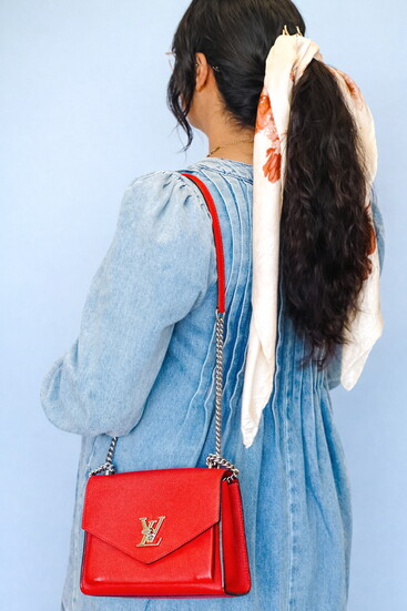 Lupita is using a scarf in her hair to match a Louis Vuitton handbag. 
