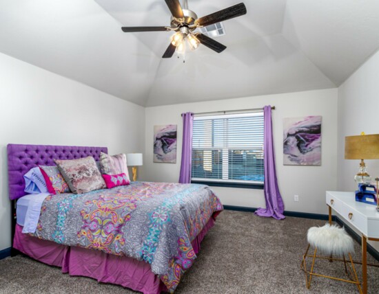 The generously sized master bedroom features a vaulted ceiling, ceiling fan and lush carpet.
