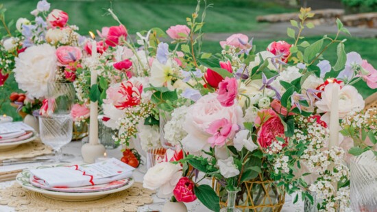 Colorful china was layered and complemented by lush florals that stretched down the table in an eclectic mix of rattan vases and stone compotes.
