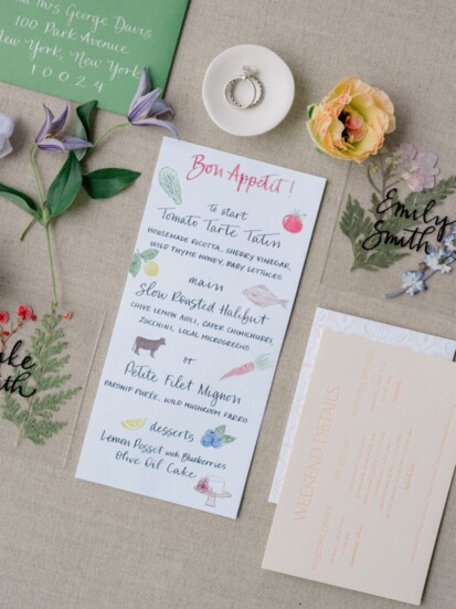 Hand painted menus - with both Erica’s art and calligraphy - tucked into the red and white scalloped napkin.