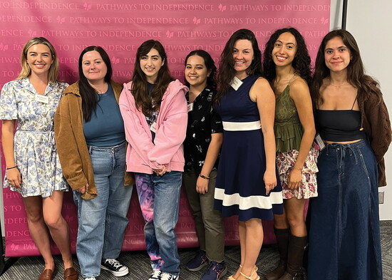 Clients gather for a photo in front of a Pathways backdrop during graduation.