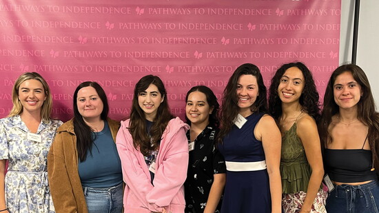 Clients gather for a photo in front of a Pathways backdrop during graduation.