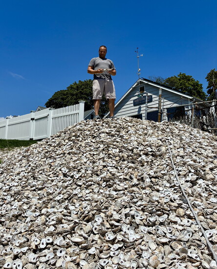 Massimo Tullio, owner of Massi Co and The Whelk, atop a pile of recycled oyster shells. Photo courtesy Massi Co.