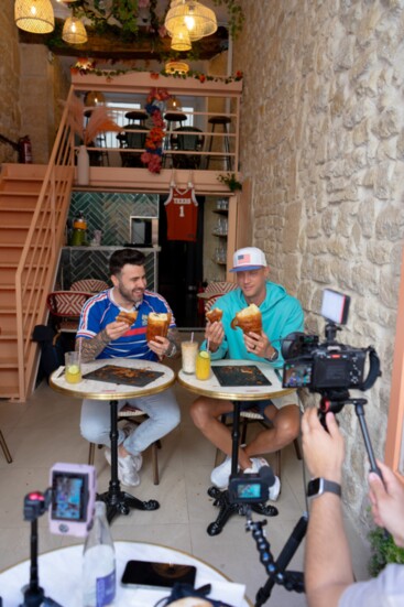 Kévin D'Andréa challenges retired decathlete Trey Hardee to a croissant-eating competition on "Breaking Baguettes" at Wonderland Brunchy in Paris. 