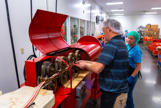 This red machine rolls & stretches the warm candy into a long strip that gets snipped into canes & hand-bent into hooks.
