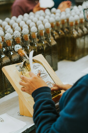 An employee carefully applies the label—one of many hands to touch each bottle before they are sent out for distribution.