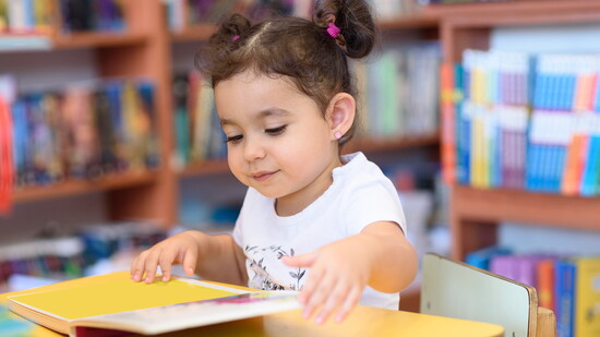 Child reading a book in a library.