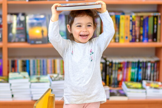 A child with a book in the children's section of a library.