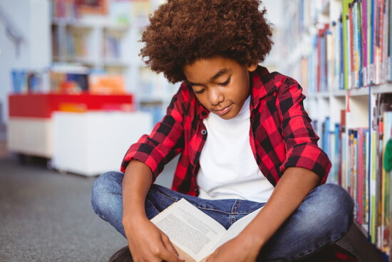 A child reading a book at a library. 
