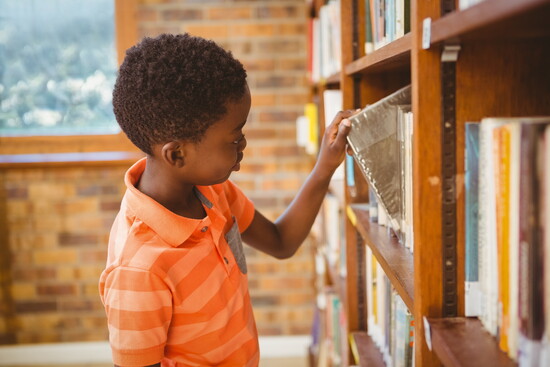 A child choosing a book at a library. 