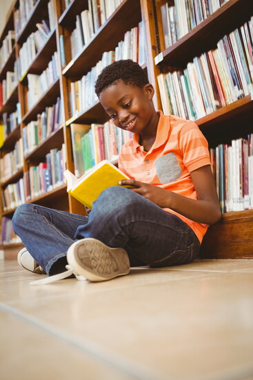 A child reading a book in a library.