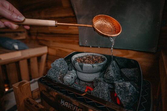 A ladle pours water over hot stones