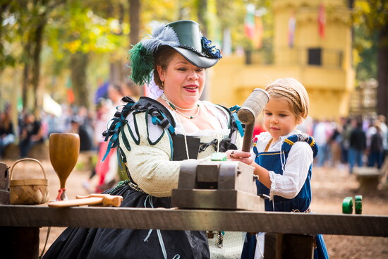 Craftswoman guides child through hands-on medieval workshop.