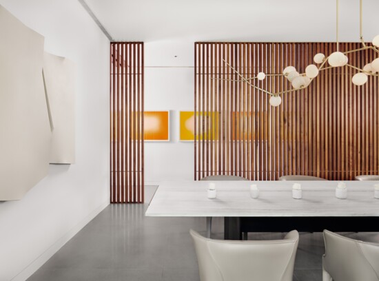 White walls and ceiling are offset by touches of color, in the modern wall art on the far wall, and by the vertical lines of the movable room divider.