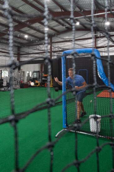 Owner Mark, soft tosses to an athlete in the batting cat