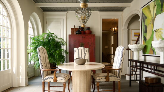 An Italian midcentury travertine table from CIIRCA Antiques anchors the room, paired with chairs upholstered in a Nobilis fabric.