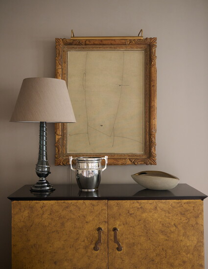 A Lucy Cope lamp sits atop a refinished Formations sideboard, beneath a Jean Marc Louis painting sourced from CIIRCA Antiques.