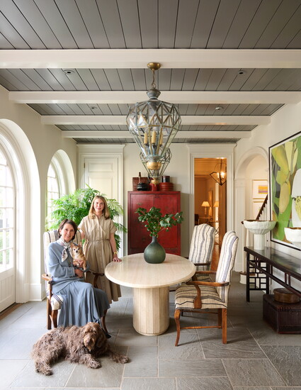 An Italian midcentury travertine table from CIIRCA Antiques anchors the room, paired with chairs upholstered in a Nobilis fabric.