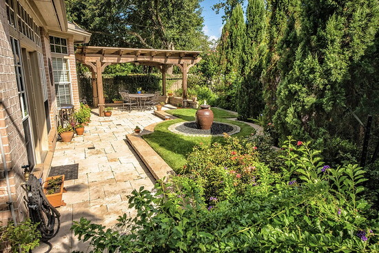 A stone terrace and pergola turn a side yard into an outdoor room, with layered planting that adds privacy, texture, and year round curb appeal.