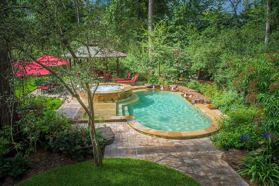 A naturalized pool design pairs curved lines with lush planting and stone decking, creating a private retreat that feels rooted in the surrounding landscape.