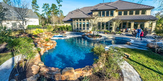 A resort style pool framed with natural stone and layered planting creates a showpiece backyard that feels designed, not added on.