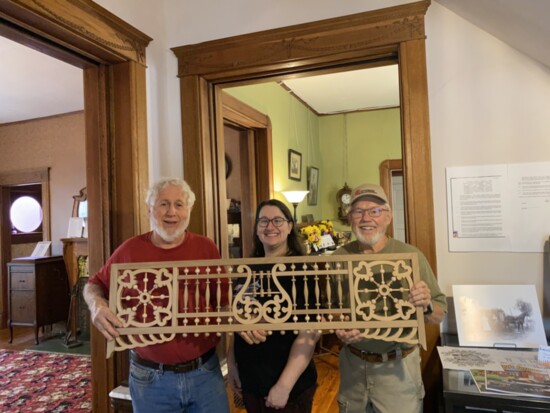 Museum director Amy Pence, with Bill Hull and Dave Dyer of the Central Oklahoma Woodturner's Association, hold up a restored scrollwork panel.