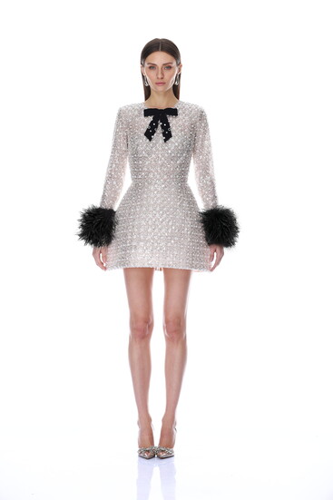 A crystal-covered silver mini dress finished with a black velvet bow and dramatic feathered cuffs
