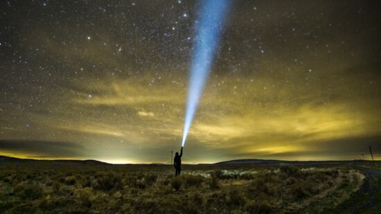 Standing beneath the expansive desert skies of Oregon's Badlands, a faint glow of distant Central Oregon light pollution is visible on the horizon.