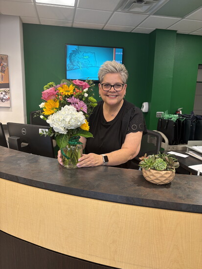 Diana Pitman receives a Dragons Care grant along with a floral arrangement by Carroll Senior High School’s Dragon Blooms students