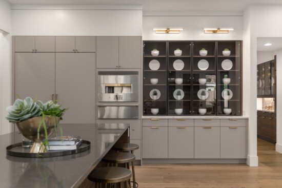 The display cabinets in both this kitchen not only provide ample storage but also create a stunning showcase for dishes and glassware.