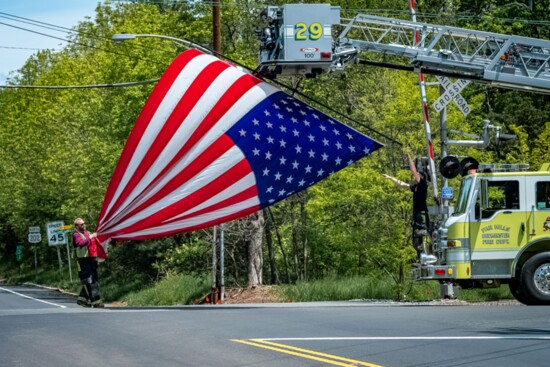 The Far Hills – Bedminster Fire Department raises a flag to salute passing cyclists during the annual Police Bike Ride.