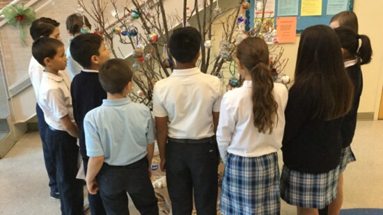 Catholic children gather around the Jesse Tree. [John Ryan / Greeley Interfaith Association]