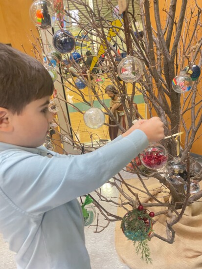 A Catholic child hangs an ornament on the Jesse Tree. [Catherine Weber-Vowell / Greeley Interfaith Association]