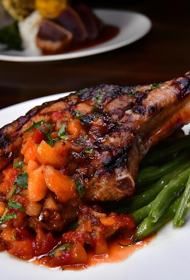 The Grilled Pork Chop with Apricot Chutney pairs a tender, herb-brined chop with roasted fingerling potatoes and market-fresh vegetables.