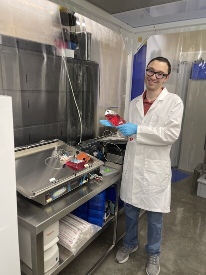 Daniel Benzel working with a bag of cell culture media and a rocking bioreactor.