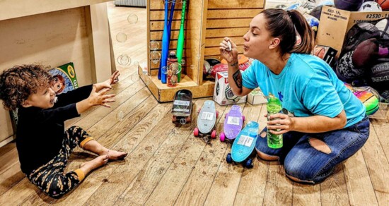 An Olive Branch volunteer plays with a child inside the store in Somerset Square.