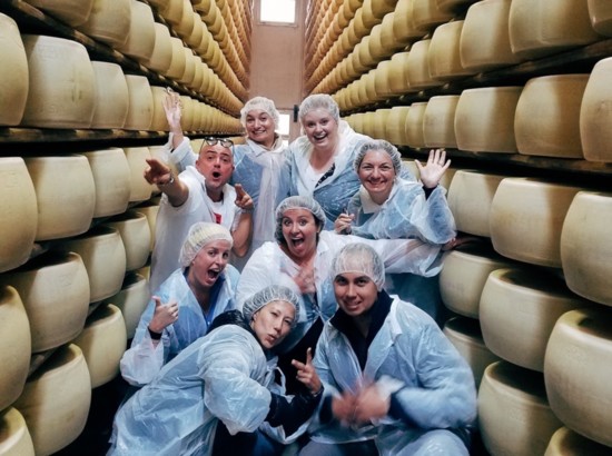 Posing with the wheels of cheese at a Parmigiano-Reggiano factory on a Heart of Italy Tour