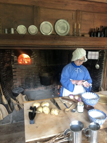 A young volunteer in period garb prepares a meal inside the historic home. 