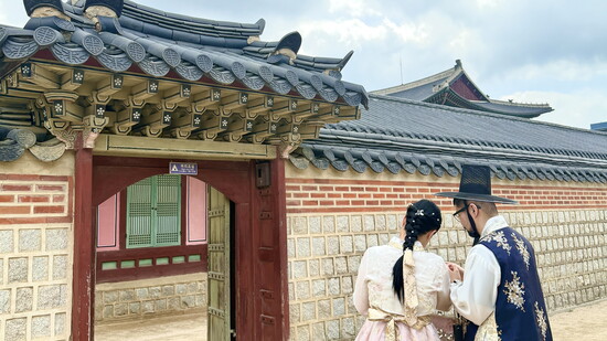 Tourists dressed in traditional hanbok study a map of the expansive palace grounds.