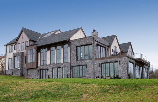 Stone facades and tiered gables create a commanding presence, blending traditional architectural proportions with expansive, modern window installations.